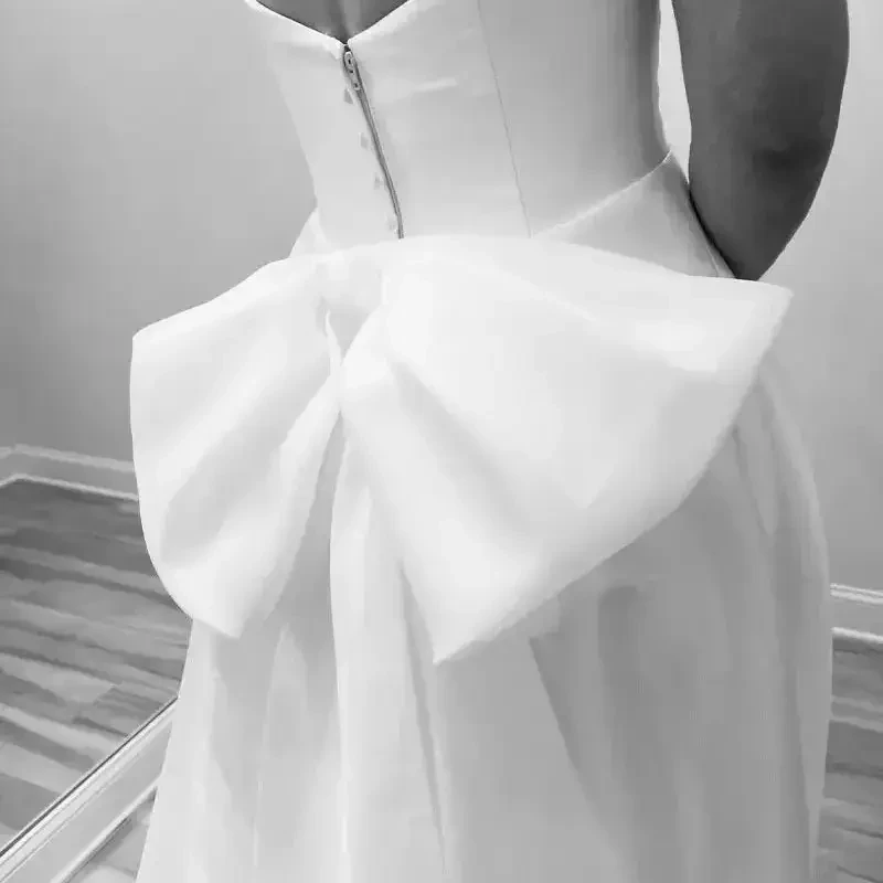 Close-up of a wedding gown featuring a dramatic oversized bow at the back.