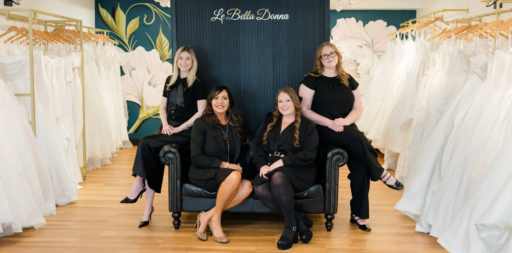 The Le Bella Donna team posing together inside the Doylestown boutique, surrounded by racks of wedding dresses.