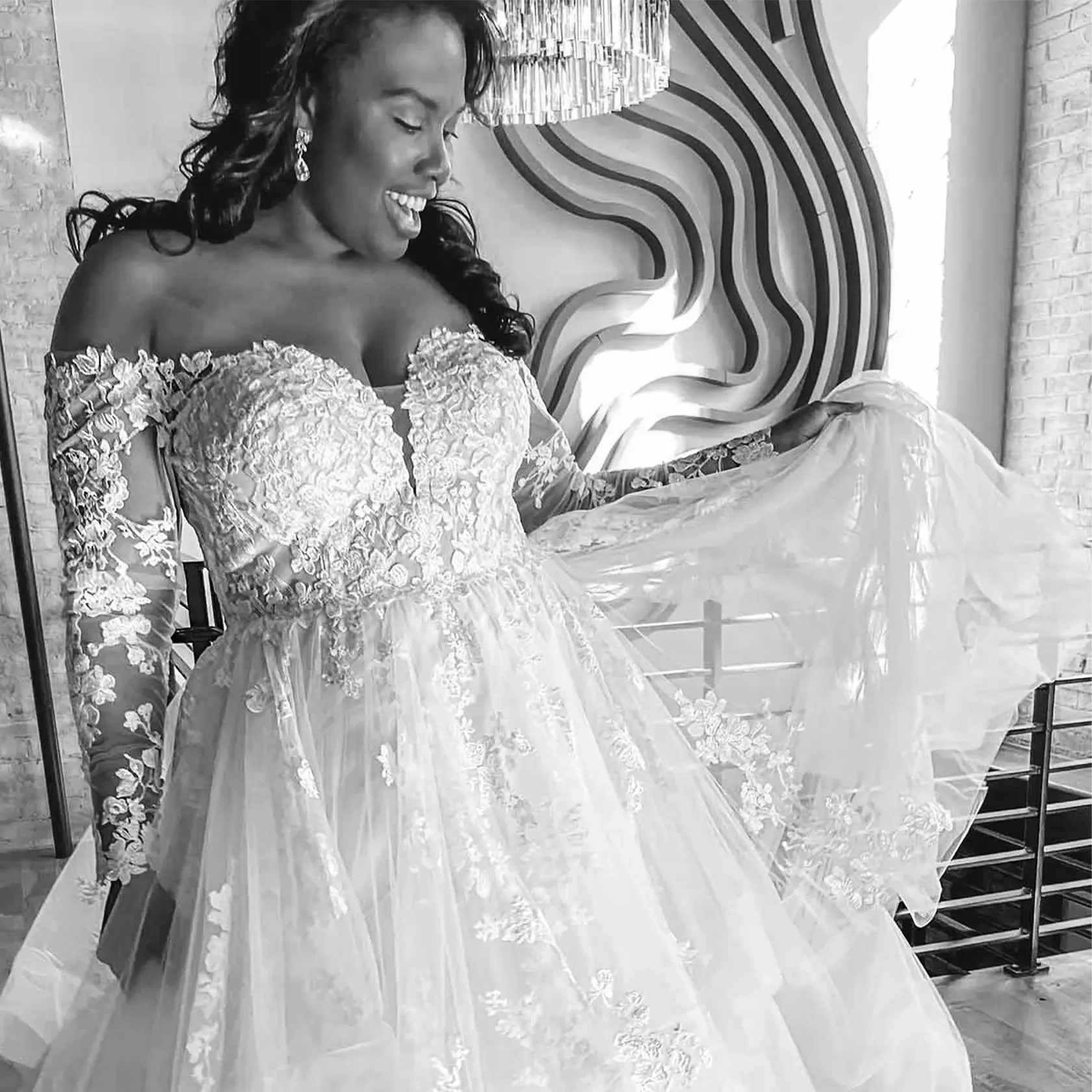 Plus-size bride wearing an off-the-shoulder lace wedding gown with long illusion sleeves and a full tulle skirt.